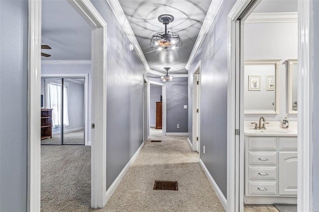 hallway featuring crown molding, sink, and light carpet