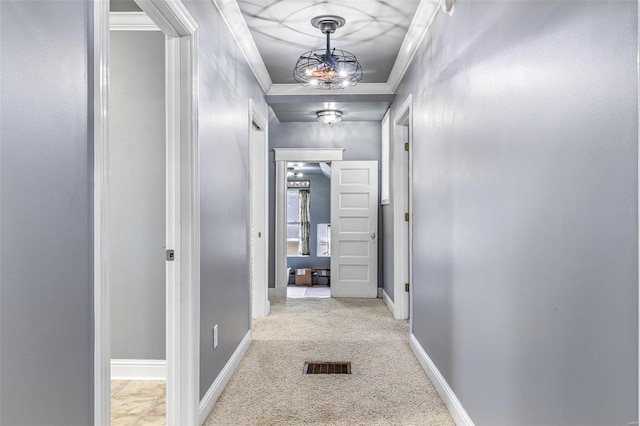 hallway featuring crown molding, light carpet, and an inviting chandelier