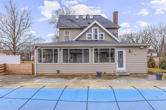 rear view of house with a sunroom, a covered pool, and a patio