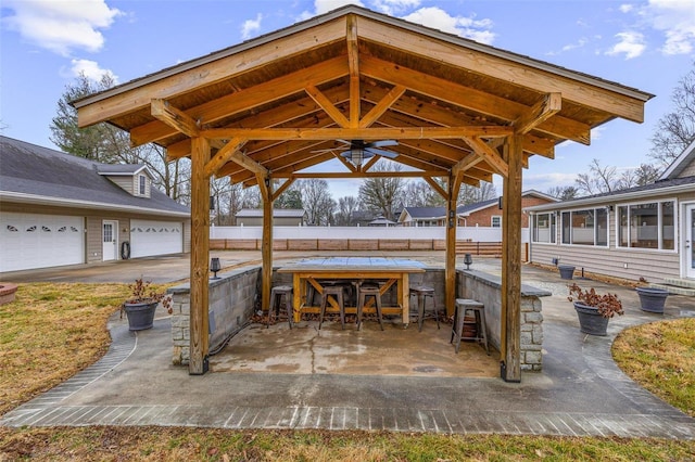 view of patio featuring a bar, ceiling fan, and a garage