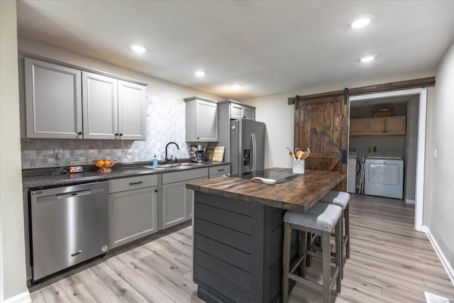 kitchen with gray cabinets, appliances with stainless steel finishes, sink, wooden counters, and independent washer and dryer