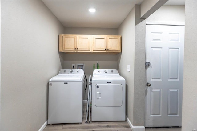 laundry room featuring cabinets, washer and clothes dryer, and light hardwood / wood-style floors