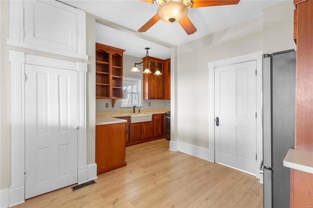 kitchen with sink, light hardwood / wood-style flooring, pendant lighting, stainless steel appliances, and ceiling fan with notable chandelier