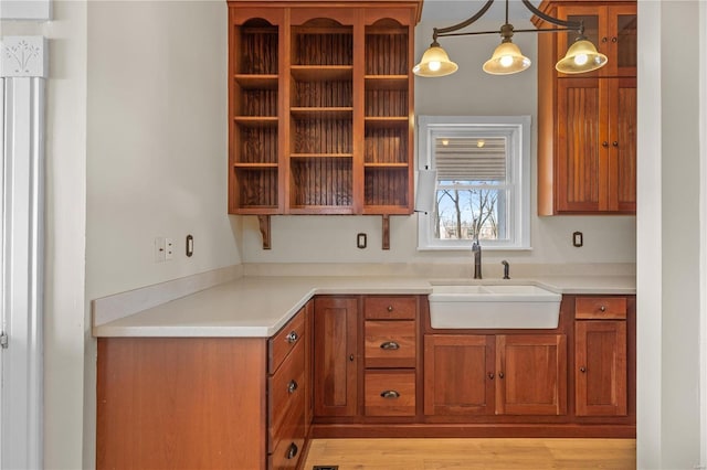 kitchen with hanging light fixtures, light hardwood / wood-style floors, and sink