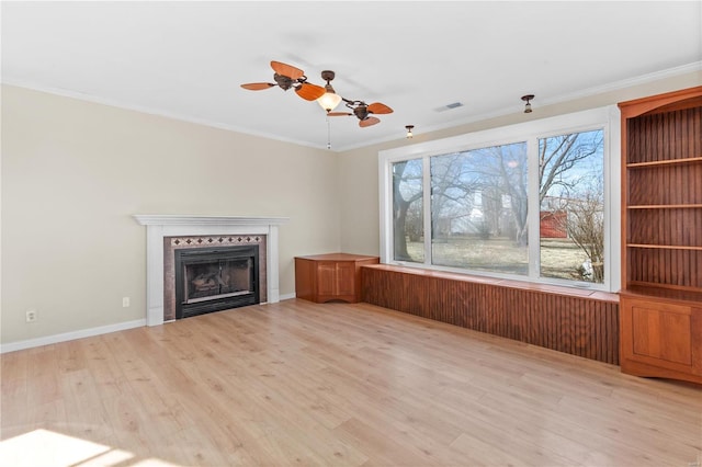 unfurnished living room with a tile fireplace, ornamental molding, ceiling fan, and light wood-type flooring