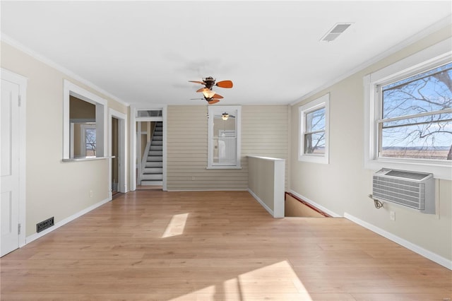 spare room with crown molding, a wall unit AC, and light wood-type flooring