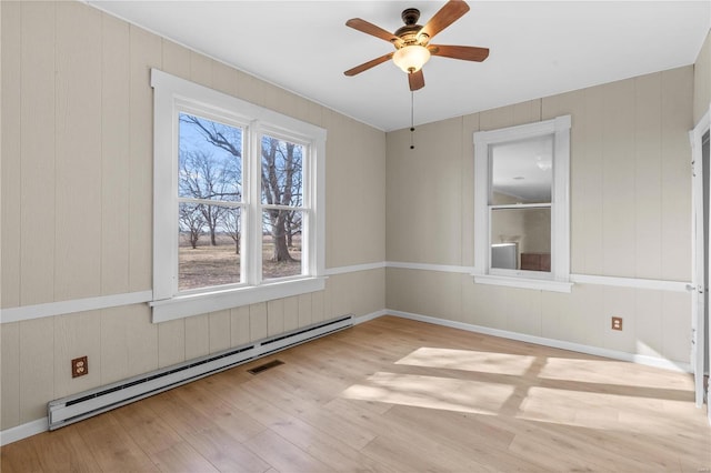 unfurnished room with baseboard heating, ceiling fan, and light wood-type flooring