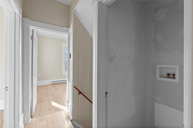 clothes washing area with washer hookup, light hardwood / wood-style floors, and a baseboard heating unit