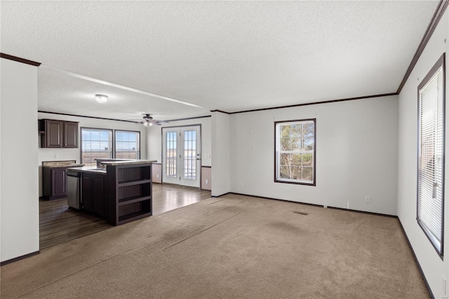 unfurnished living room with crown molding, french doors, a textured ceiling, and carpet flooring