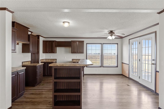 kitchen with dark brown cabinetry, ornamental molding, dark hardwood / wood-style floors, a kitchen island, and ceiling fan