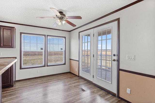 entryway featuring french doors, crown molding, a textured ceiling, light hardwood / wood-style flooring, and ceiling fan