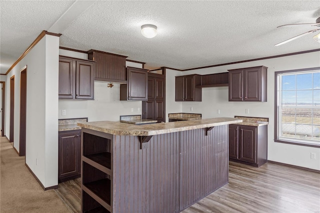 kitchen featuring crown molding, dark brown cabinetry, a kitchen breakfast bar, and a center island