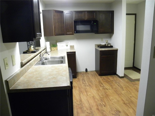 kitchen with dark brown cabinets, sink, and light wood-type flooring