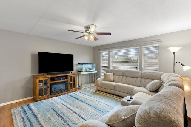 living room featuring wood finished floors, a ceiling fan, and baseboards