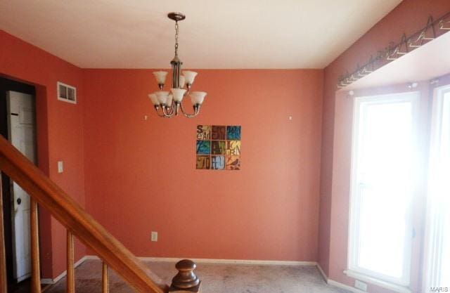 interior space with an inviting chandelier and carpet flooring