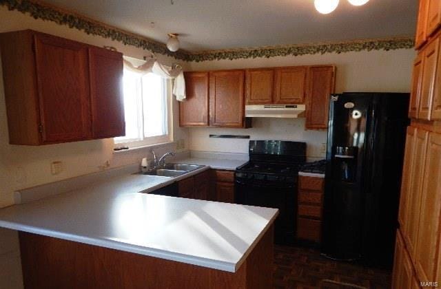 kitchen with sink, dark parquet flooring, black appliances, and kitchen peninsula