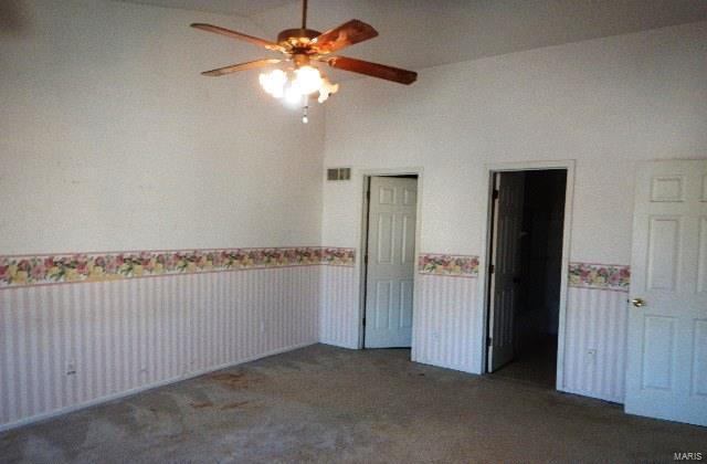 carpeted empty room with vaulted ceiling and ceiling fan