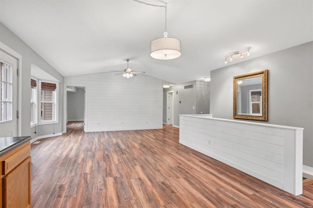 unfurnished living room with brick wall, lofted ceiling, dark hardwood / wood-style floors, and ceiling fan