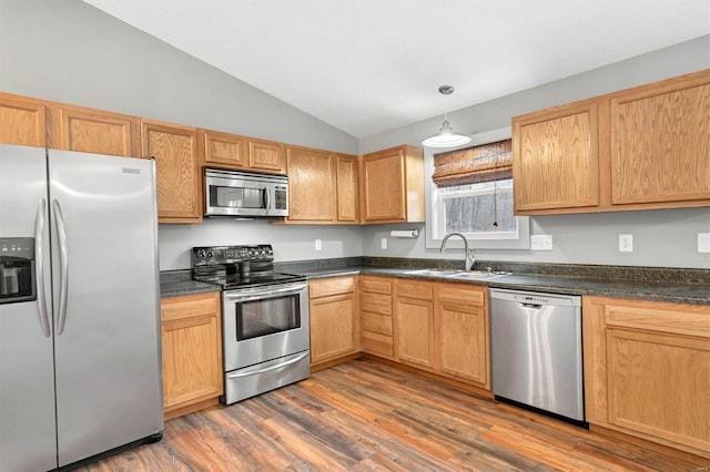 kitchen with lofted ceiling, sink, dark hardwood / wood-style flooring, hanging light fixtures, and stainless steel appliances