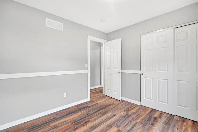 unfurnished bedroom with dark wood-type flooring and a closet