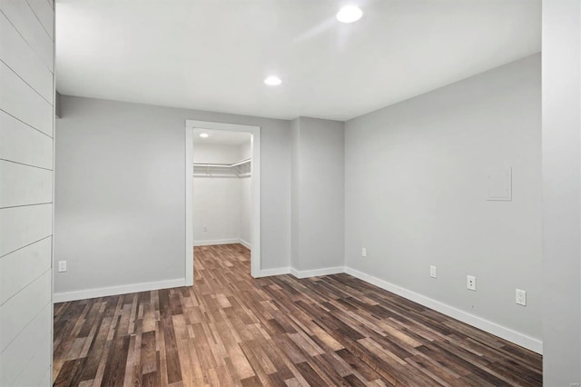 unfurnished bedroom featuring dark hardwood / wood-style flooring, a walk in closet, and a closet