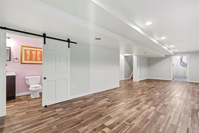 basement featuring a barn door and hardwood / wood-style floors