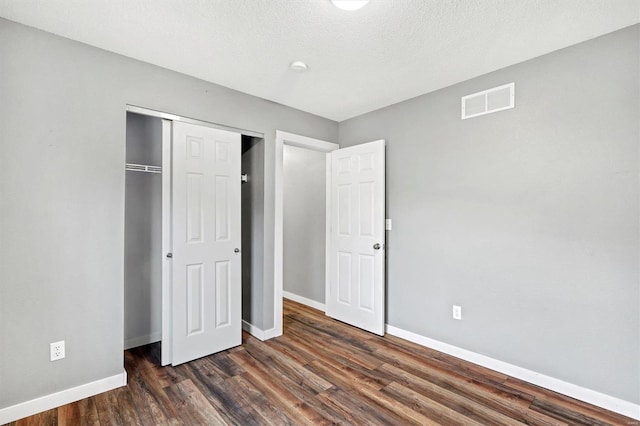 unfurnished bedroom featuring dark hardwood / wood-style flooring, a closet, and a textured ceiling