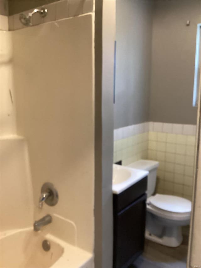 full bathroom with vanity,  shower combination, tile walls, and toilet