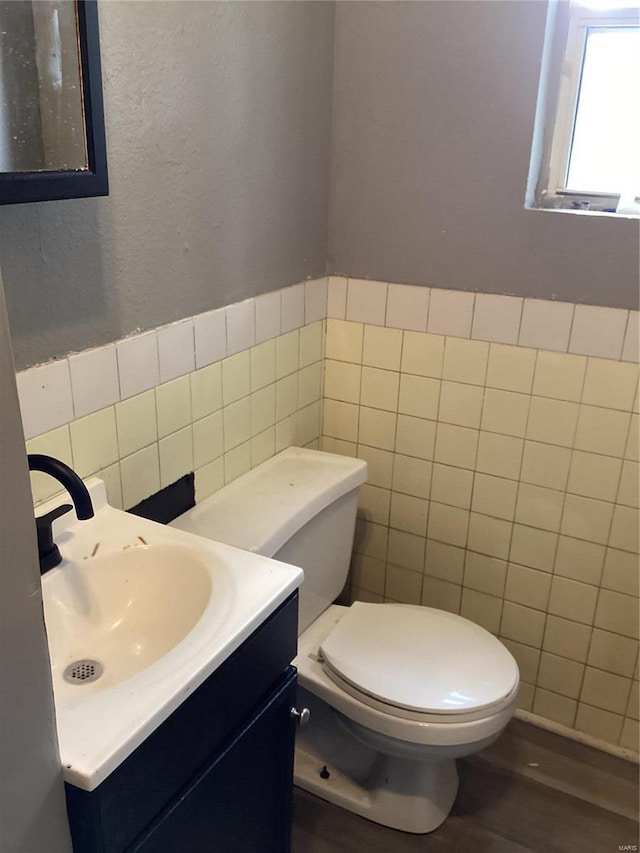 bathroom featuring vanity, toilet, wood-type flooring, and tile walls