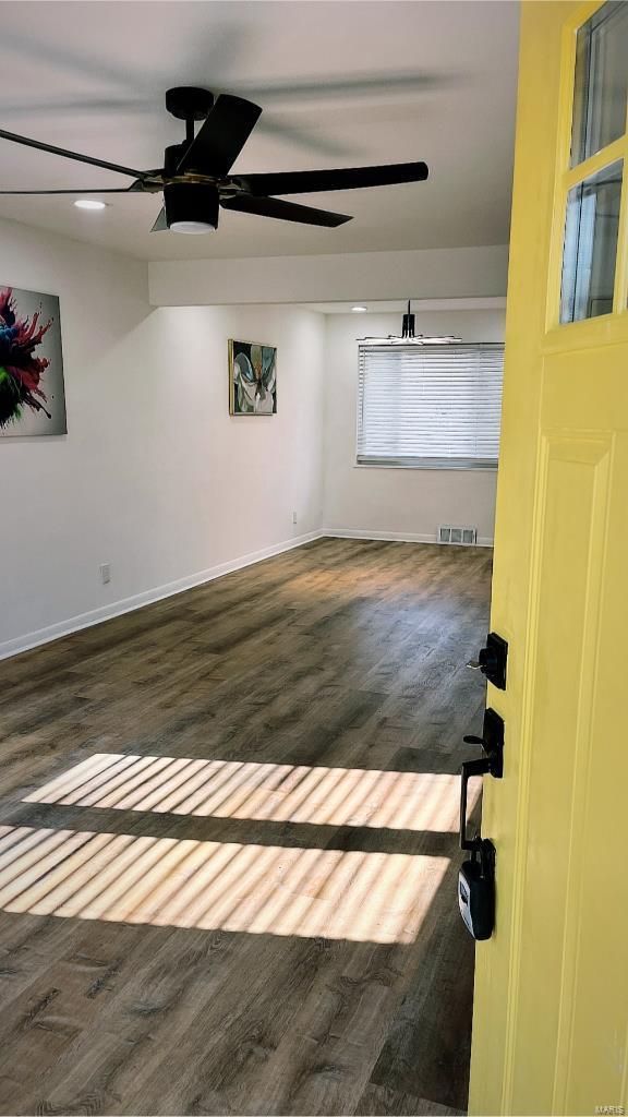 empty room with ceiling fan and dark hardwood / wood-style flooring