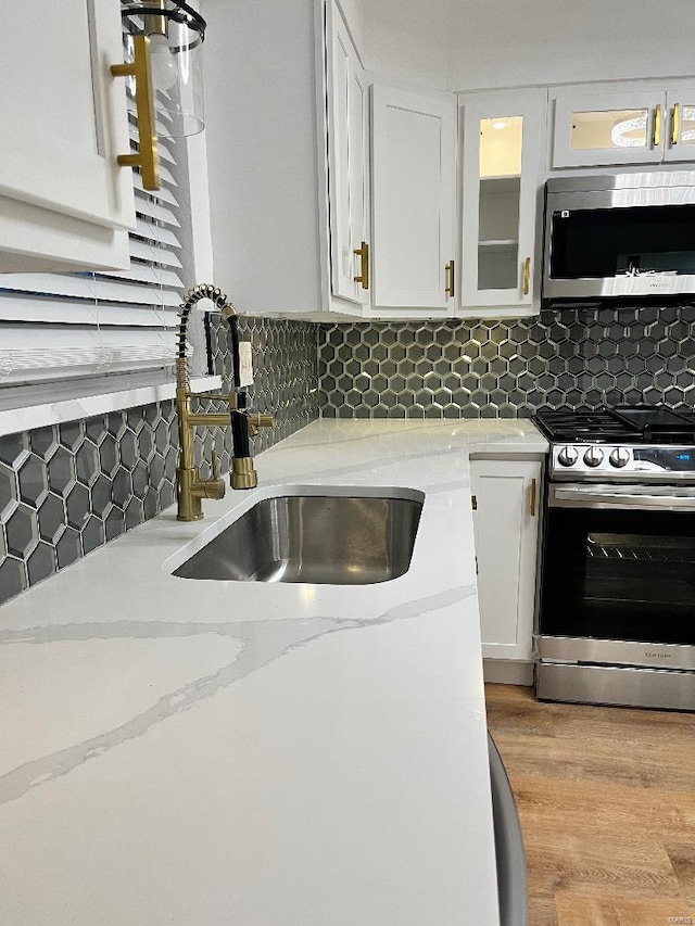 kitchen with white cabinetry, stainless steel appliances, sink, and decorative backsplash