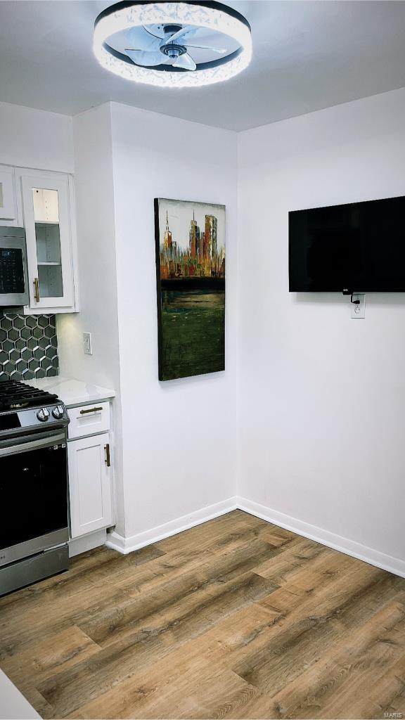 kitchen with backsplash, appliances with stainless steel finishes, dark hardwood / wood-style floors, and white cabinets