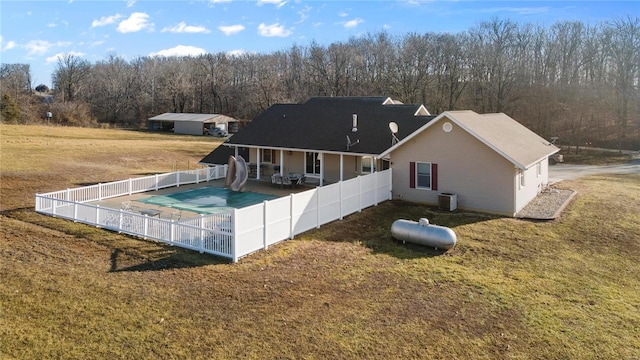 back of house featuring central AC unit, a lawn, a covered pool, and a patio area