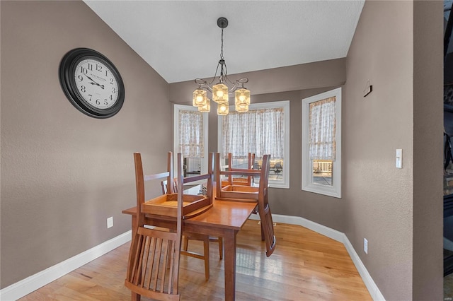 dining area featuring vaulted ceiling, a chandelier, and light wood-type flooring