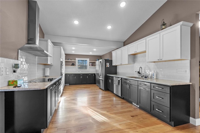 kitchen featuring wall chimney exhaust hood, sink, light wood-type flooring, appliances with stainless steel finishes, and white cabinets