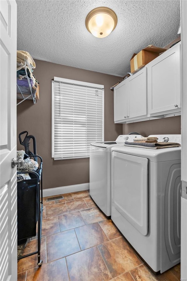 laundry area with cabinets, separate washer and dryer, and a textured ceiling