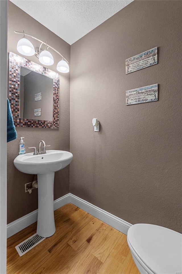 bathroom with sink, hardwood / wood-style flooring, a textured ceiling, and toilet