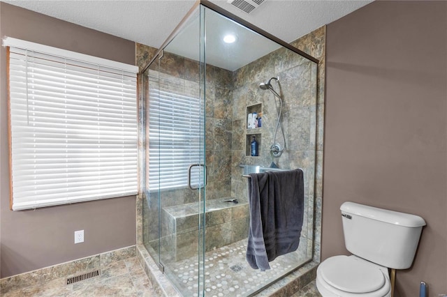 bathroom with walk in shower, toilet, and a textured ceiling