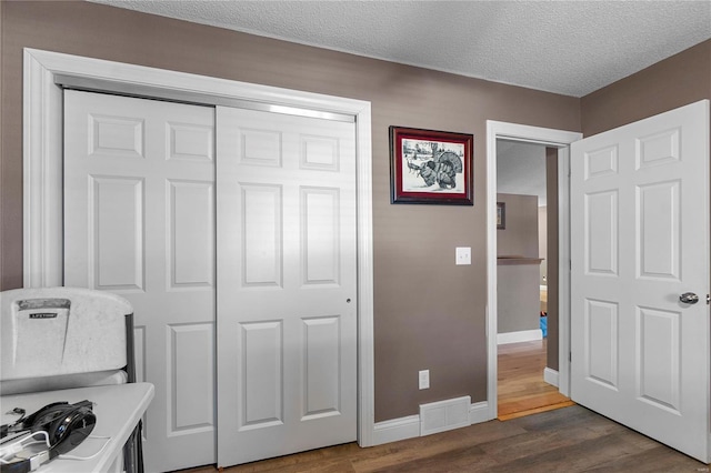 bedroom featuring a closet, dark hardwood / wood-style floors, and a textured ceiling