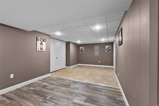 basement featuring a drop ceiling and light hardwood / wood-style floors