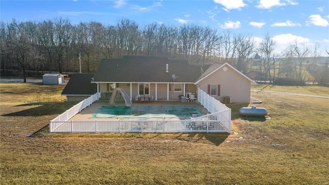 back of property featuring a covered pool, a patio area, a shed, and a lawn