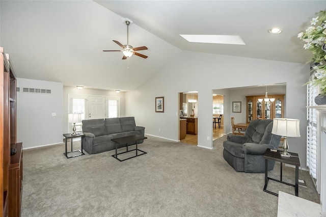 carpeted living room featuring ceiling fan with notable chandelier, high vaulted ceiling, and a skylight