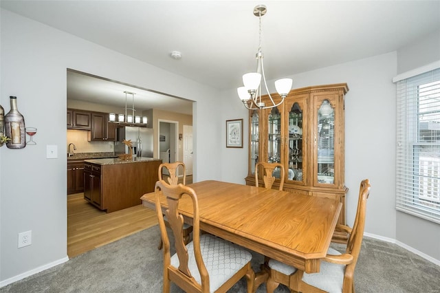 dining room featuring an inviting chandelier, light colored carpet, and sink