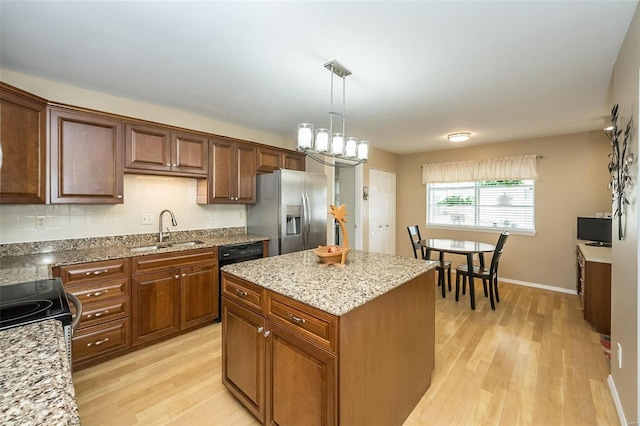 kitchen with sink, a center island, black dishwasher, stainless steel refrigerator with ice dispenser, and light wood-type flooring