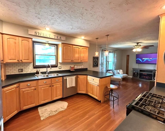 kitchen with sink, dark hardwood / wood-style flooring, hanging light fixtures, stainless steel dishwasher, and kitchen peninsula