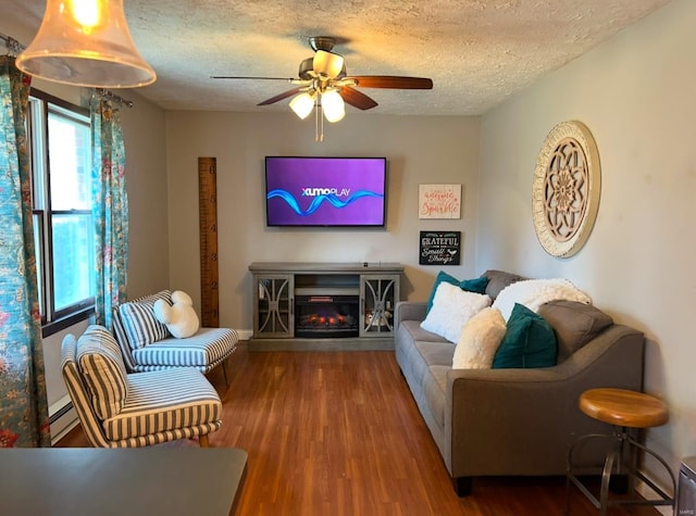 living room with ceiling fan, a baseboard radiator, wood-type flooring, and a textured ceiling