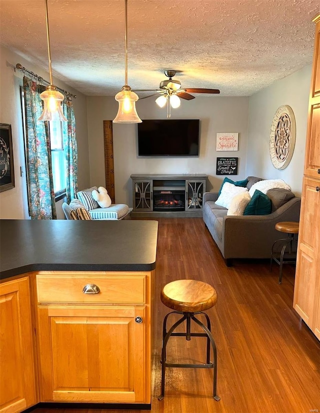 kitchen featuring hanging light fixtures, ceiling fan, dark hardwood / wood-style floors, and a textured ceiling