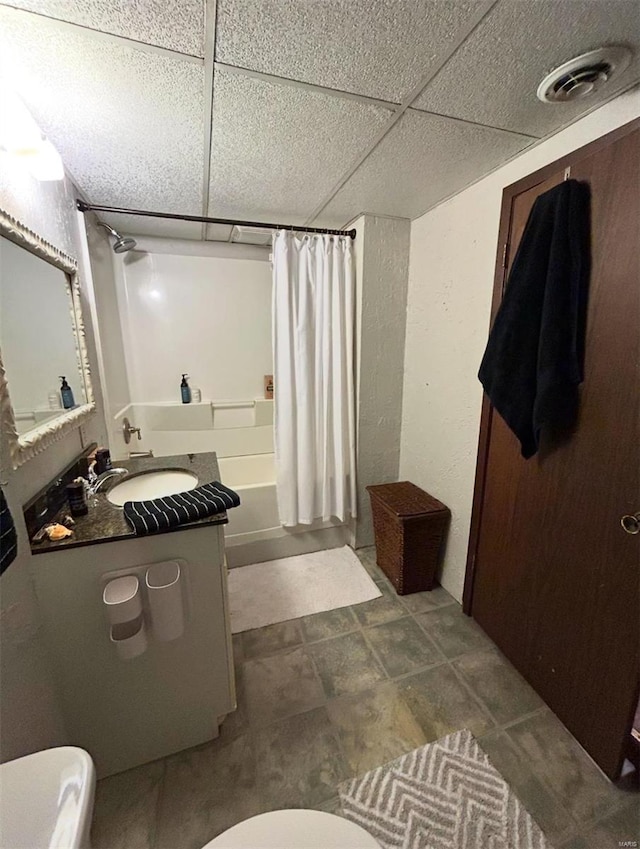 full bathroom with shower / bath combination with curtain, vanity, toilet, and a drop ceiling