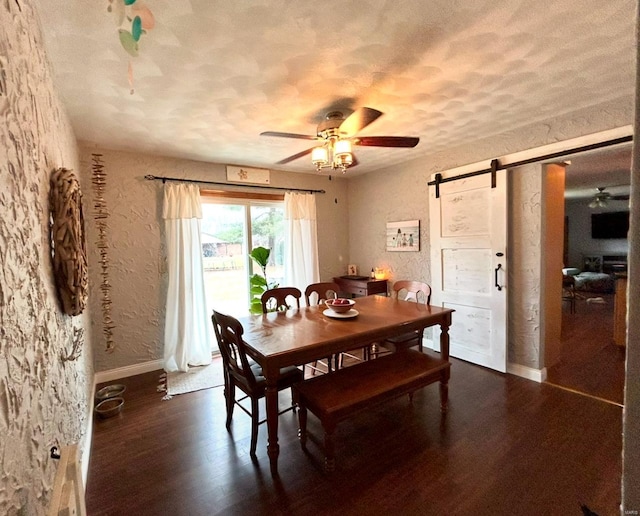 dining room with ceiling fan, a barn door, dark hardwood / wood-style flooring, and a textured ceiling