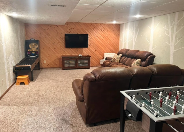 carpeted living room featuring a paneled ceiling and wooden walls